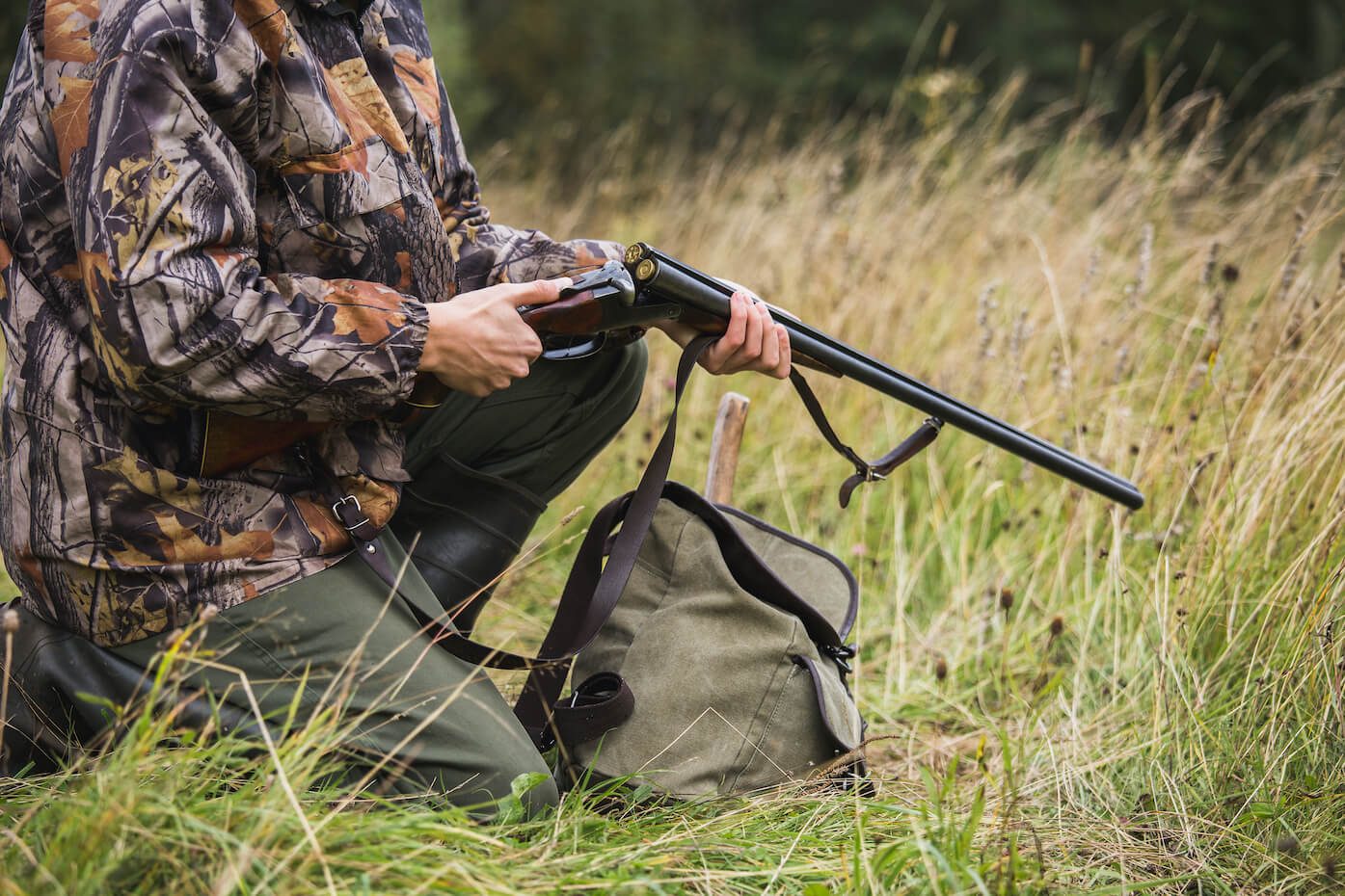 Jäger mit Flinte im hohen Gras bei der Jagd